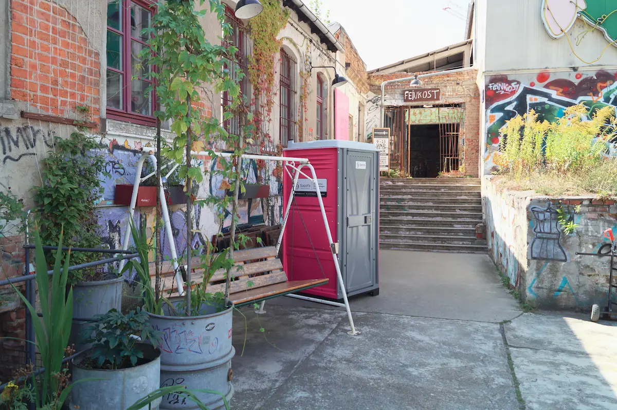Pink-graue-miettoilette-draußen-vor-einem-alten-großen-haus-der-perfekte-ort-für-eine-private-feier-dixi-klo-für-1-tag-mieten-und-top-vorbereitet-sein